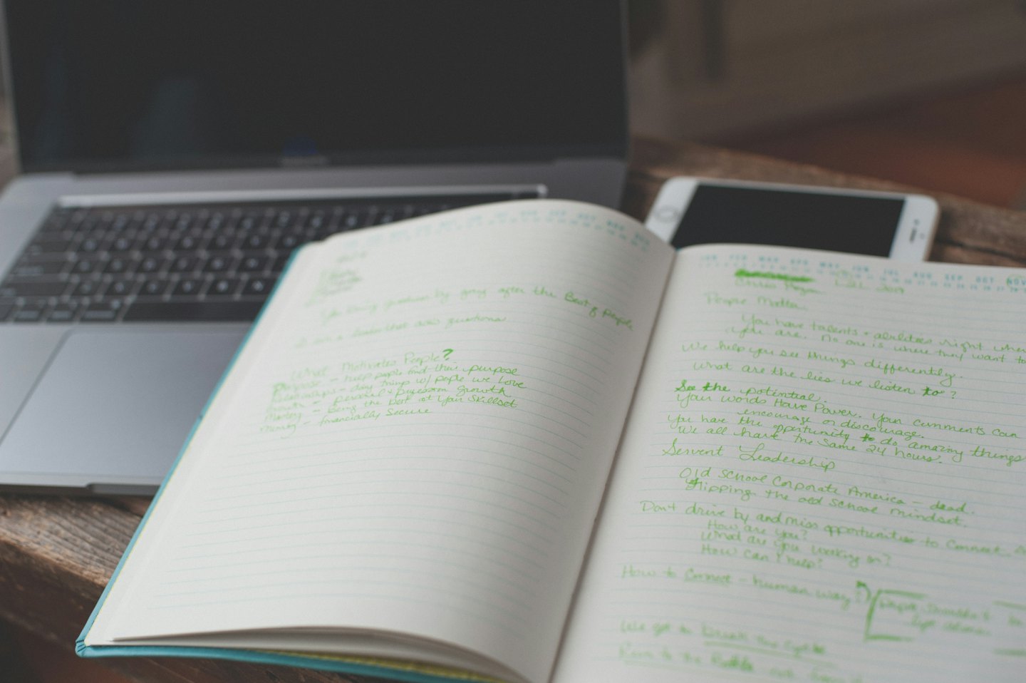 Cahier avec des notes à l'encre verte sur un bureau en bois.